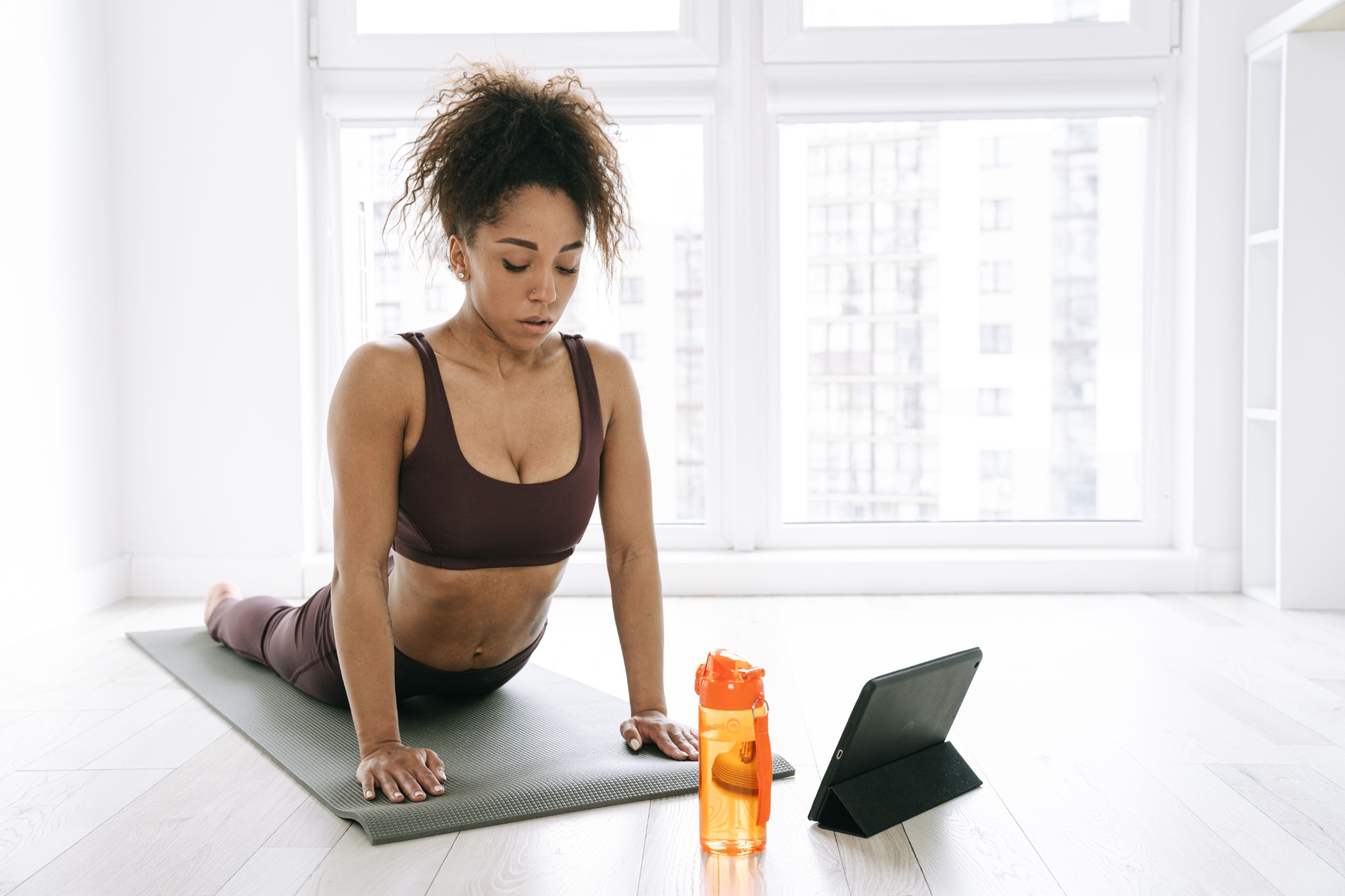 Woman practicing yoga at home with a tablet